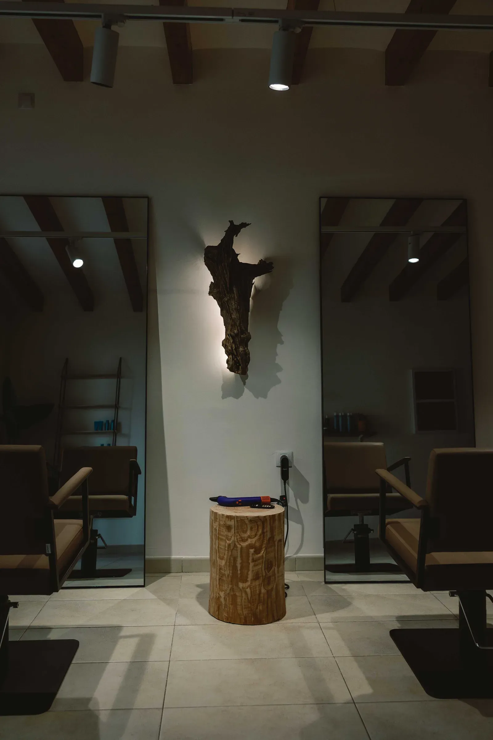 Wnętrze Andrew Kruczek Boutique Hair Studio — dwa stanowiska z lustrami, drewniany pieniek i belkowany sufit